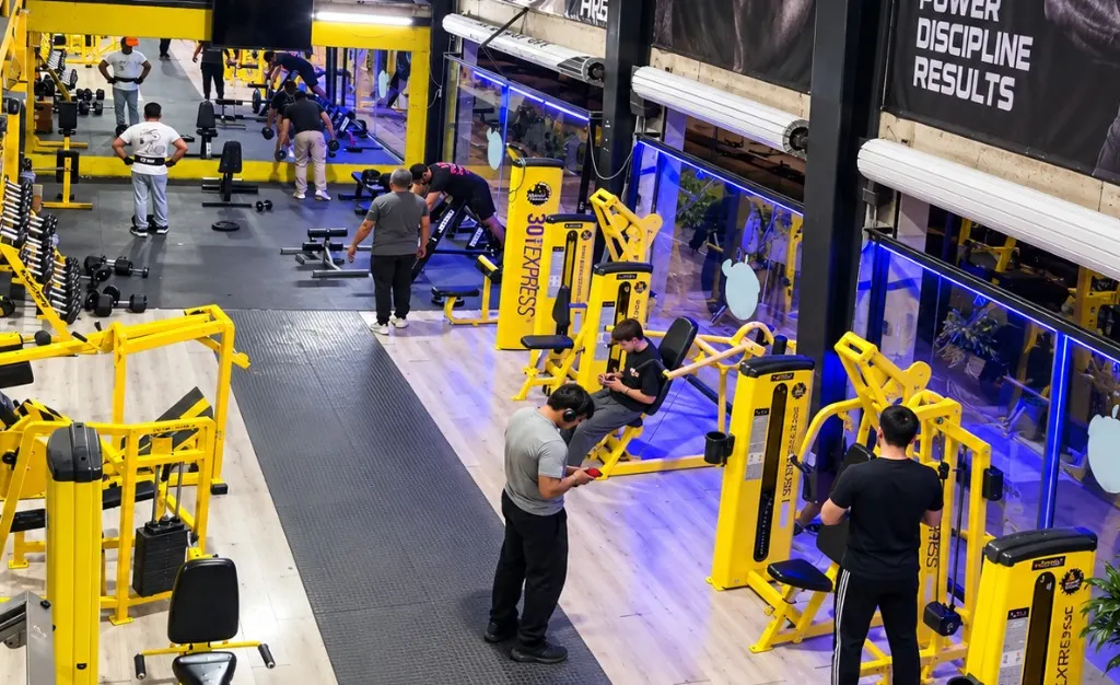 Vista amplia del piso de Gym & Fitness Jazar en Villa Sur, con máquinas amarillas y gente entrenando