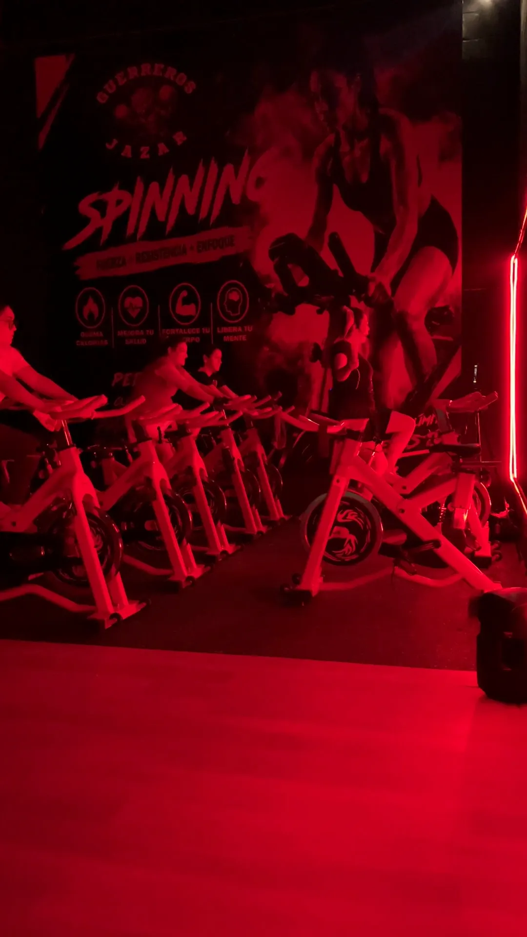 Clase de spinning de Guerreros Jazar con bicicletas blancas y luz magenta