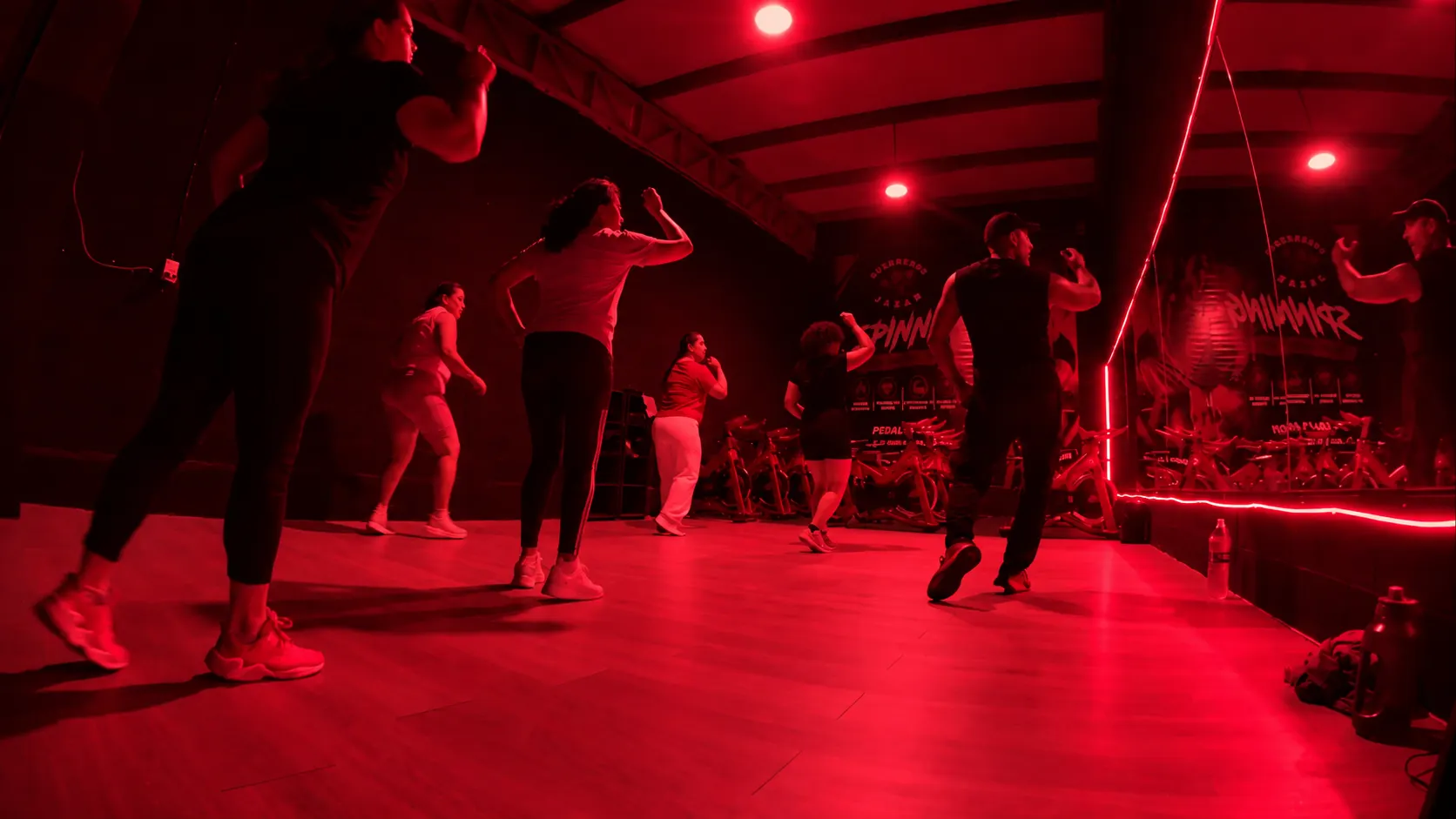 Clase de zumba de Guerreros Jazar con gente bailando bajo luz magenta
